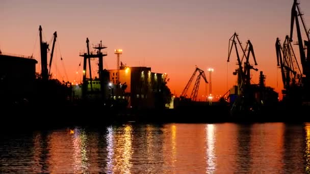 Port maritime au coucher du soleil de la journée. Beau coucher de soleil rouge sur le fond des grues portail . — Video