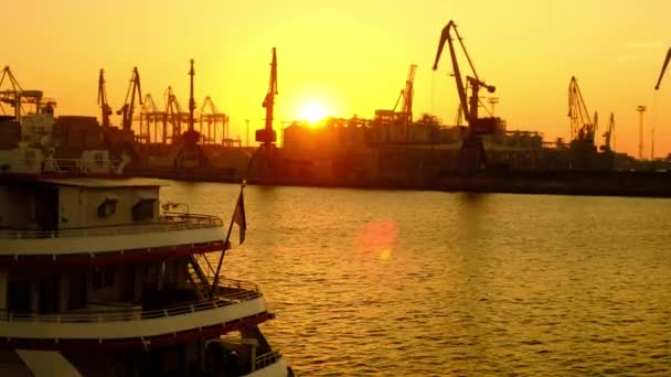 Het schip staat op de pier op de achtergrond van lading kranen. Ochtendgloren op de kust. — Stockvideo