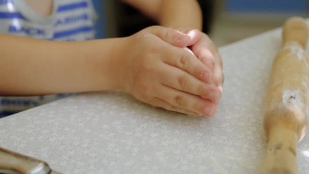 Los niños rodillo para la masa. El niño amasa la masa con las manos . — Vídeos de Stock