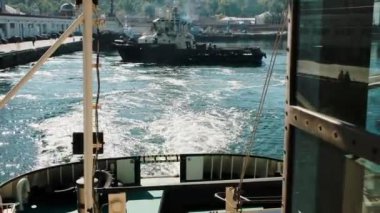 Römorkör diğer römorkör sonra sahile gidiyor. Dikiz üzerinden güverte. Martılar ve suyun