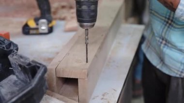 adam ahşap tahta delikler yapmak eski Dubai sokakta ahşap atölyesinde elektrikli matkap ile eller görünümü Kapat 