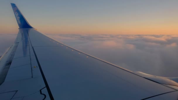 Sluiten passagiersvliegtuig vleugel tegen bewolkte hemel bij zonsondergang — Stockvideo
