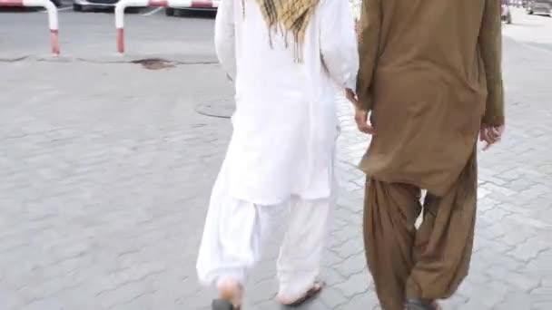 Indietro due uomini in abiti arabi camminano unendo le mani sul marciapiede — Video Stock