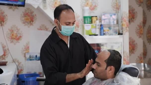 Barbeiro lubrifica o rosto do cliente depois de fazer a barba na barbearia — Vídeo de Stock