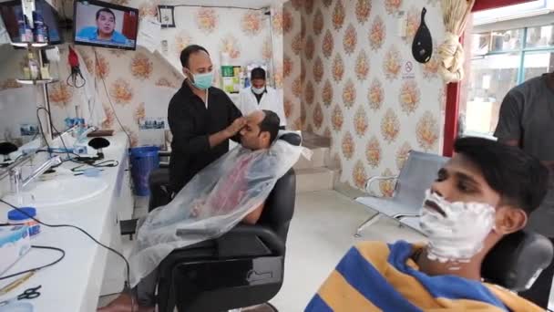 Клиент сидит с пеной на лице в магазине уличных парикмахеров — стоковое видео