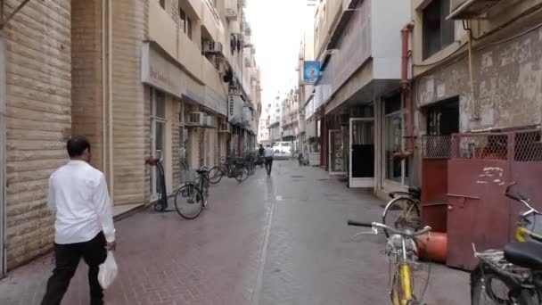 Muž chodí podél pěší zóna s obchody a zaparkovaných jízdních kol — Stock video