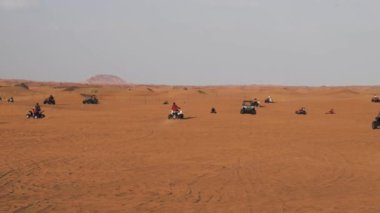 Turistler Dubai, Birleşik Arap Emirlikleri yakınındaki Arap çöl yoluyla quad bisiklet sürmek
