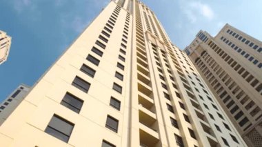 Dubai, Birleşik Arap Emirlikleri. Gökdelenler Dubai. Yüksek katlı apartmanın Dubai mavi gökyüzü. Pürüzsüz kamera hareketi. Radikal düşük açılı yüksek katlı bina video