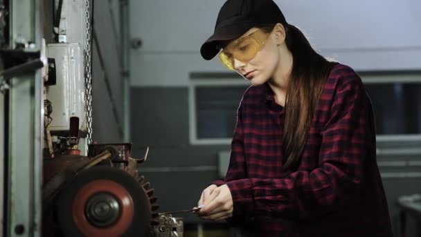 Belle fille en chemise à carreaux, casquette noire et lunettes, travaillant sur une rectifieuse. Femme dans la profession masculine — Video