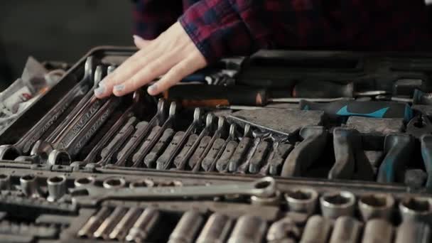 Mãos femininas suaves de uma jovem, um mecânico de automóveis, com uma manicure e unhas pintadas, contra o fundo de um conjunto de chaves abertas e outros dispositivos para reparação de automóveis . — Vídeo de Stock