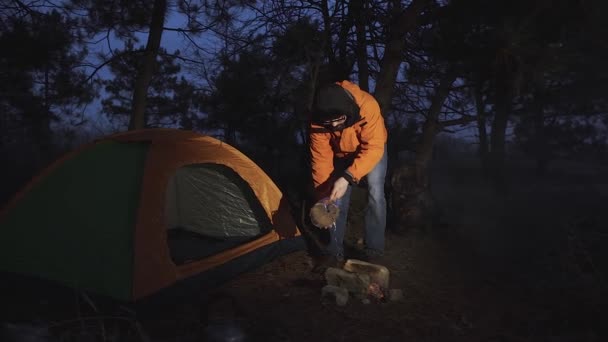 Um turista derrama água sobre o fogo que ele tinha acendido antes de entrar em sua tenda em que ele iria passar a noite . — Vídeo de Stock