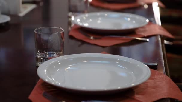 Mesa grande y elegante pulida, sobre la que hay platos y vasos. Ajuste de mesa en un restaurante aristocrático — Vídeos de Stock