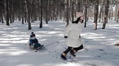 Genç bir aktif anne ateşler arasında çalışır ve onun çocuk oturur kızak, çeker.