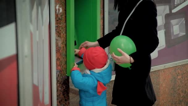 Мама учит ребенка пользоваться банкоматом — стоковое видео