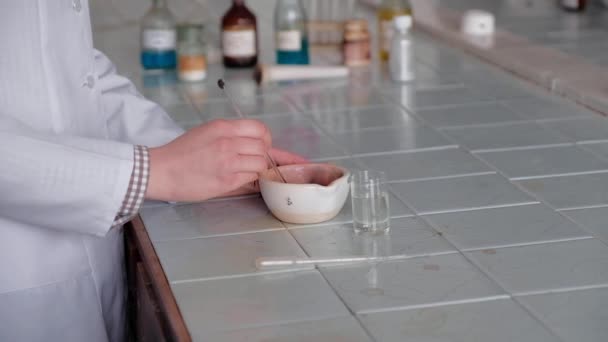 白いコートを着た少女は、特別な皿で化学溶液をかき混ぜる. — ストック動画
