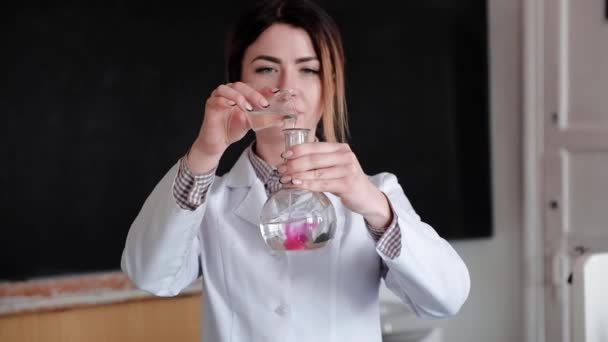 Retrato de una científica examinando frascos con diferentes sustancias químicas en un laboratorio médico — Vídeos de Stock