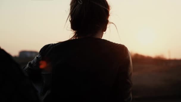Porträtt av en ung flicka som sitter lutad på en sportcykel och beundrar solnedgången. — Stockvideo