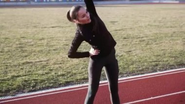 Stadyumda güzel genç kadın farklı fitness egzersizleri gerçekleştirir.