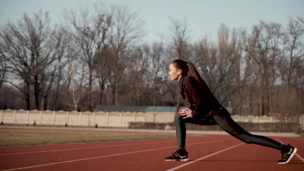 Chica joven en el estadio realiza ejercicios de estiramiento muscular . — Vídeos de Stock