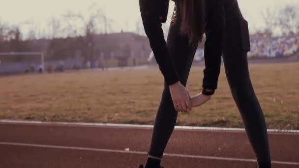 Brunette girl at the stadium in the sun performs fitness exercises. — Stock Video