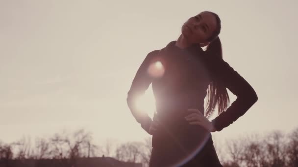 Brunette fille au stade au soleil effectue des exercices de fitness . — Video