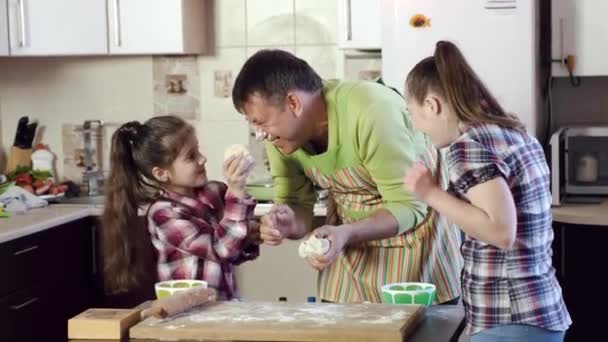 Father cheers up daughters and jaws small thick dough pieces — Stock Video