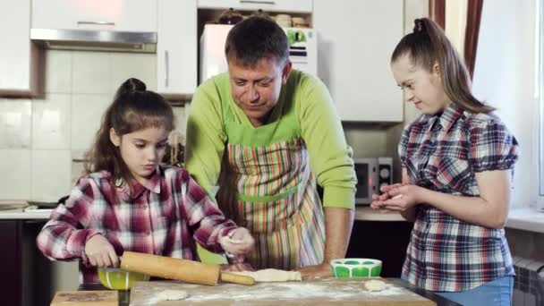Ein Familienvater in der Küche im Gespräch mit seinen Töchtern beim Teigkochen. — Stockvideo