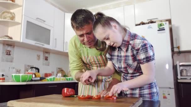 Отец учит свою дочь с синдромом Дауна, как резать овощи . — стоковое видео