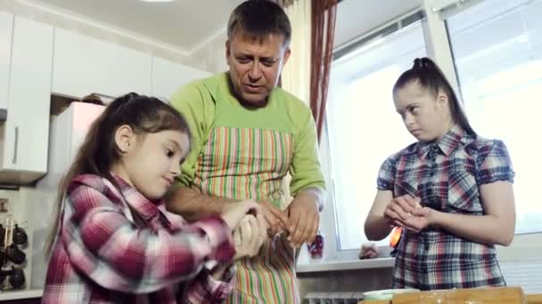 Батько і дві дочки, одна з них з синдромом Дауна, роблять тісто разом на кухні . — стокове відео