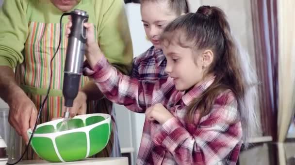 Dad teaches daughters, one of whom with Down syndrome, to use a kitchen mixer. — Stock Video