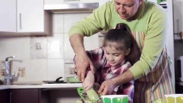 A girl under the guidance of his father grate zucchini. — Stock Video