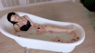 mavi sütyen bayan çiçek yaprakları ile köpüklü banyo yatıyor