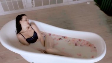 Seksi kız süt ile banyo almak için mutlu, üst açı.