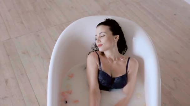 A woman lies in a bathtub with milk and enjoys spa treatments. — Stock Video