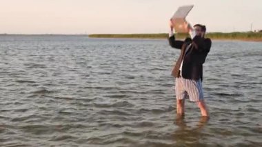 Bir iş takım elbise ve deniz ortasında hiçbir pantolon bir dizüstü bilgisayar ile bir Freelancer coşkulu sonucu sevinçler.