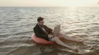 Bir dizüstü bilgisayar ile çalışan bir çocuk şişme daire üzerinde denizin ortasında girişimci.