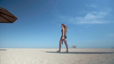 şort içinde uzun bacaklı kız ıssız bir plaj geçmiş saman mantar boyunca yürüyüş.