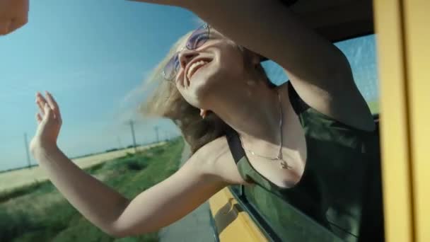 Feliz joven mujer se inclina por la ventana del coche — Vídeos de Stock