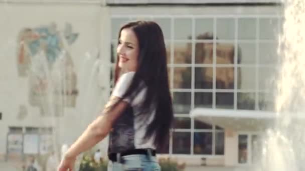 Modernly dressed girl on the background of the city fountain in high spirits. — Stock Video