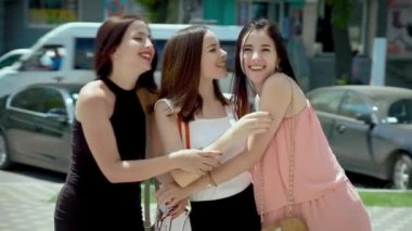 Üç şık kadın sokakta bir araya geldi, güldü ve sohbet etti.