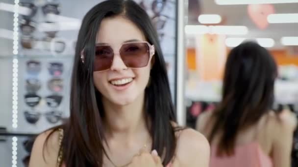 Flickan snurrar framför en spegel försöker på solglasögon. — Stockvideo