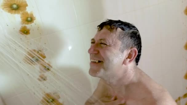 En man utan tand i munnen njuter av en varm dusch. — Stockvideo