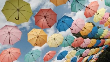 Mavi gökyüzünün arka planında çok renkli şemsiyeler.