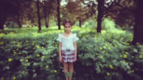 Una niña, de 9 años, se encuentra en medio de una densa vegetación y flores amarillas. stop motion — Vídeo de stock