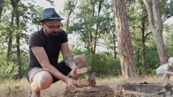 De man maakte een vuur en gehakte hout voor een picknick in het bos. — Stockvideo