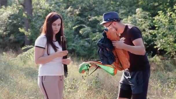 Een man en een meisje opzetten van een toeristische tent in het bos samen. — Stockvideo