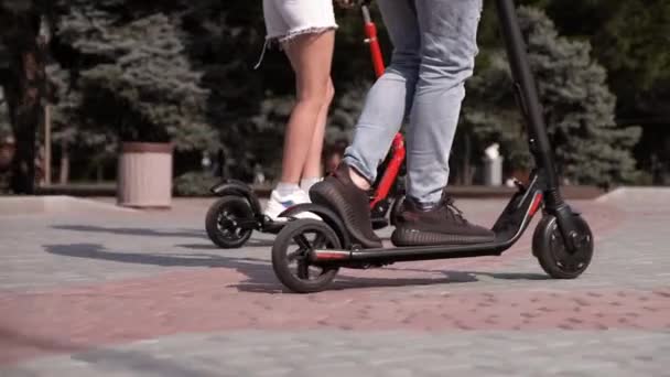 Close-up de um cara e uma menina montando uma scooter elétrica . — Vídeo de Stock