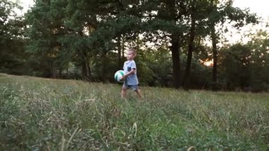 Ebeveynleri ve aile arkadaşları olan bir çocuk orman glade bir top oynar.