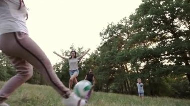 Ebeveynleri ve aile arkadaşları olan bir çocuk orman glade bir top oynar.