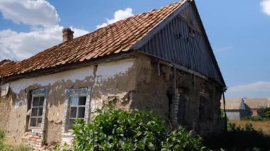 Kırmızı kiremitlerle kaplanmış harap durumdaki eski bir kır evi.
